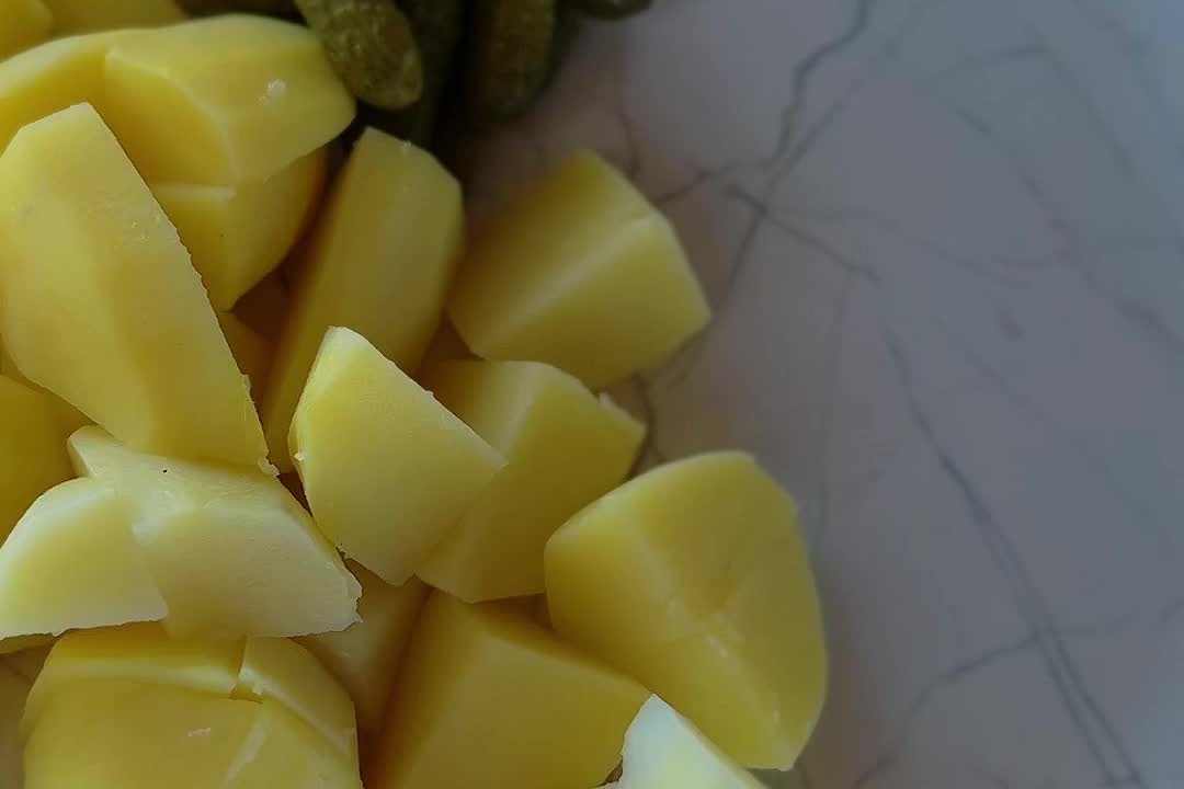 Отварной молодой картофель кусками и маринованные корнишоны на тарелке